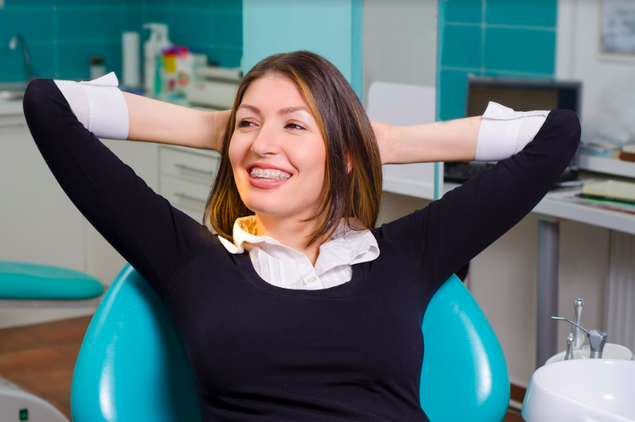 woman in dentist chair smiling with metal braces on teeth