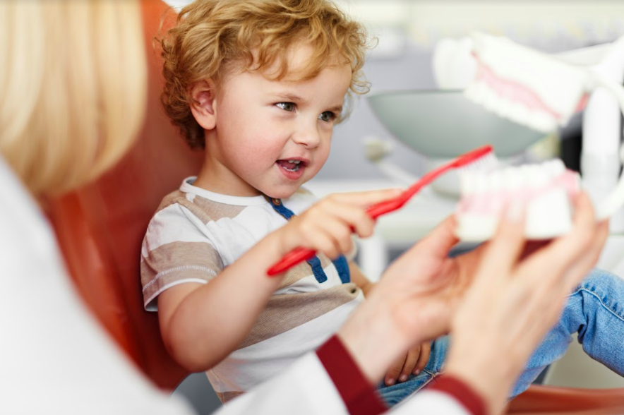 pediatric-patient-in-dentist-chair-practicing-teeth-brushing